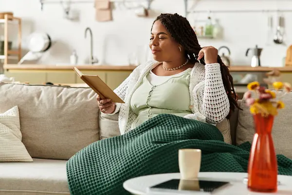 Genç bir Afrikalı Amerikalı kadın evde dinlenirken huzurlu bir sabah okumanın keyfini çıkarıyor..