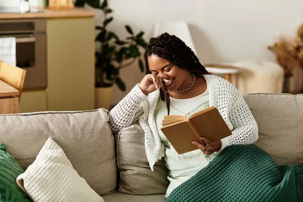 Genç bir Afrikalı Amerikalı kadın, huzurlu bir sabah kitabının tadını çıkararak evinde dinleniyor..