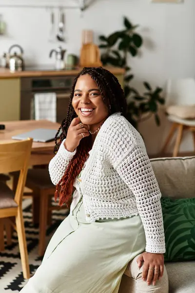 Genç bir Afrikalı Amerikalı kadın evinde rahat bir şekilde oturup huzurlu bir sabah havasını kucaklıyor..