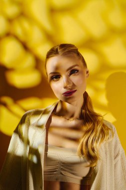 Genç ve güzel bir kadın, sıcak sarı ışık ve desenlerle kendine güvenerek ayakta duruyor..