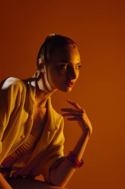 Büyüleyici, sıcak bir parıltıyla genç bir kadın zarafetini ve tarzını gösterirken zarif bir şekilde poz veriyor..