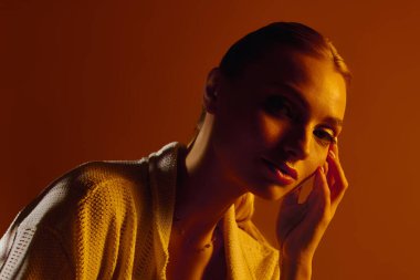 Parlak ışık, düşünceli bir şekilde poz verirken genç ve güzel bir kadının moda tarzını vurgular..