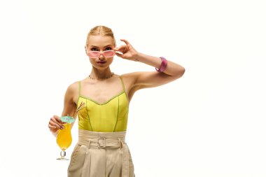 Güzel genç bir kadın tropikal bir içecekle poz veriyor, kendine güveni tam moda ve tarz sahibi..