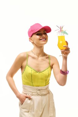 Parlak giyimli kadın gülümsüyor, elinde ferahlatıcı bir içecek, neşe saçıyor ve yaz havası yayıyor..