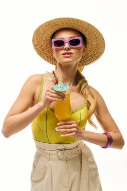 Parlak giyimli kadın güneşli gökyüzünün altında yaz titreşimleri yayarken renkli bir içkinin tadını çıkarıyor..