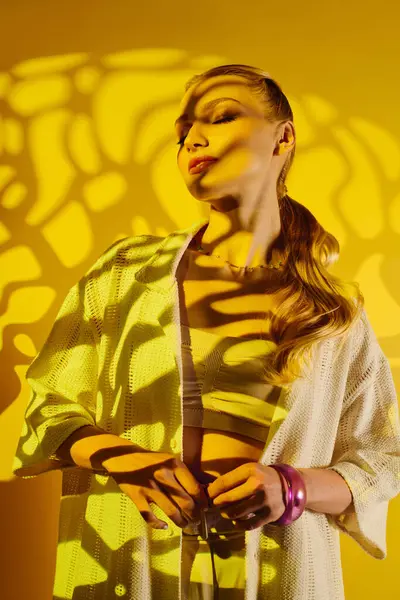 Genç ve güzel bir kadın kendine güvenerek ayakta duruyor, gölgeler vücudunda dans ediyor, canlı bir zemin..