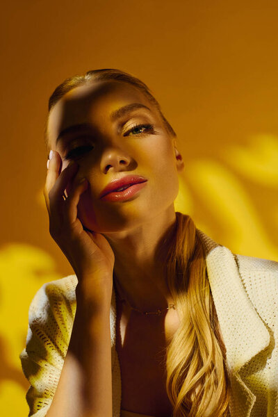 Молодая женщина с сияющей красотой демонстрирует свое чувство моды на ярком желтом фоне.