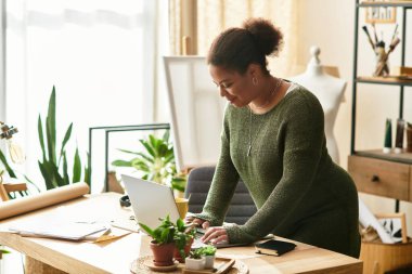 Yeşilliğin ortasında projelerine dalmış bir kadınla parlak bir zanaat atölyesi..