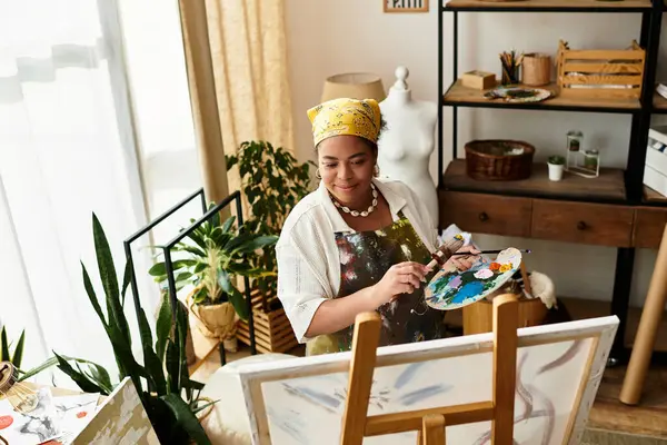 Güzel bir kadın, bitki ve malzemelerle çevrili bir zanaat atölyesinde neşeyle resim yapıyor..