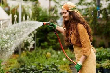 Türbanlı genç bir kadın neşeyle sular yemyeşil bir serada çiçek açar..