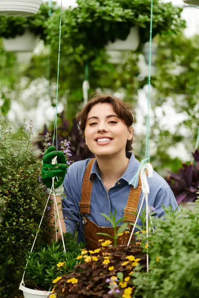 Genç bir kadın hayat dolu bir serada bitkilerle ilgileniyor, mutluluk saçıyor..