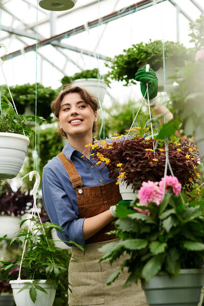 A cheerful gardener tends to beautiful hanging plants in her greenhouse, enjoying her green thumb.