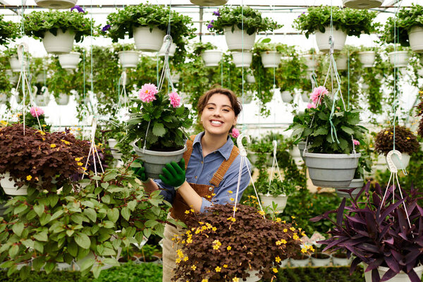 Young woman delights in planting colorful blooms while tending to her thriving greenhouse garden.