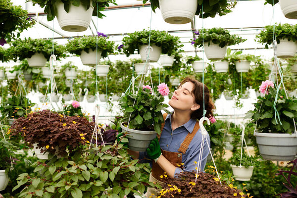 A young gardener delights in cultivating colorful flowers within a lively greenhouse space.