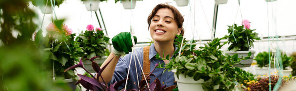 A joyful gardener tends to her flourishing plants in a bright greenhouse, surrounded by greenery, banner