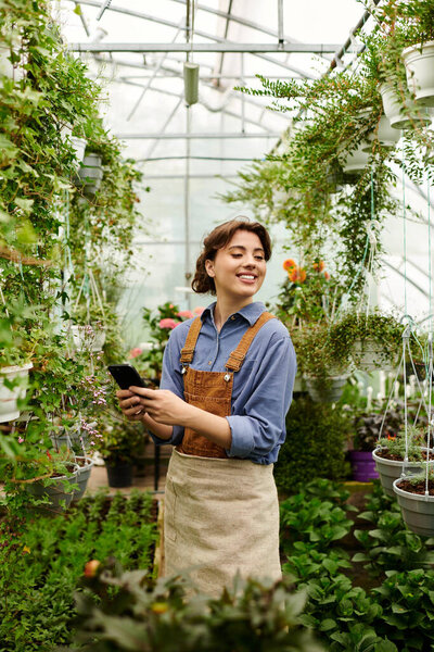 A young woman embraces her passion for gardening, surrounded by lush plants in a greenhouse.