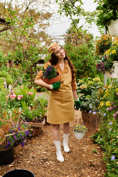 A cheerful woman in a headscarf cares for her plants amidst lush greenery and blooms.
