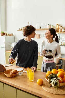 Bir çift birlikte kahvaltıdan zevk alır, gülümsemelerini ve gülüşlerini sıcak mutfaklarında paylaşırlar..