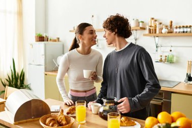 Bir çift mutfaklarında rahat bir sabah geçirir, gülümser ve kahveyi paylaşır..