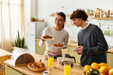 Bir çift, kahvaltı hazırlarken gülümsemeyi paylaşır, sevgi ve beraberlik ortamı yaratır..