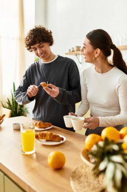 Neşeli çift evde sıcak bir kahvaltı yapar, birlikte hamur işlerinin ve taze meyve suyunun tadını çıkarırlar..
