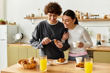 Bir çift kahvaltıdan zevk alır, gülümsemelerini ve yemeklerini sıcak mutfaklarında paylaşırlar..