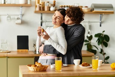 Güneşli bir mutfakta, bir çift neşe dolu bir kahvaltı paylaşır..