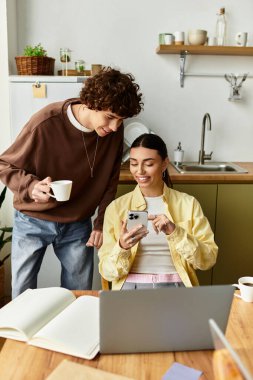 Sevgi dolu çiftler evlerinin mutfağında birbirlerine eşlik etmekten zevk alırlar, akıllı telefon ekranına gülümserler..