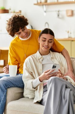 Sevgi dolu bir çift rahat bir koltukta rahatlar, birbirlerinin ve telefonlarının keyfini çıkarırlar..