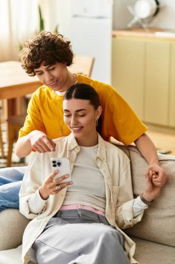 Neşeli bir çift, birlikte vakit geçirmekten zevk alır. Kanepede birbirimize sarılırken telefona bakarlar..