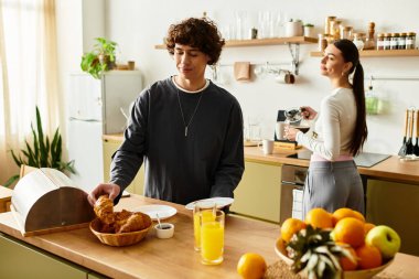 Sevgi dolu çift, taze ürünlerle süslenmiş sıcak ve davetkar bir mutfakta rahatlamış bir sabah yemeğini paylaşıyor..