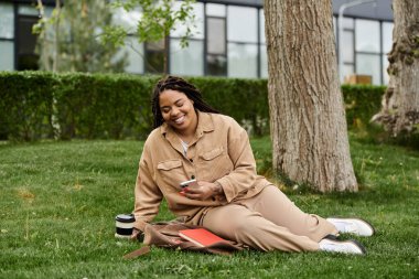 Üniversite öğretmeni huzur içinde çimde dinleniyor ve telefonunun keyfini çıkarıyor..