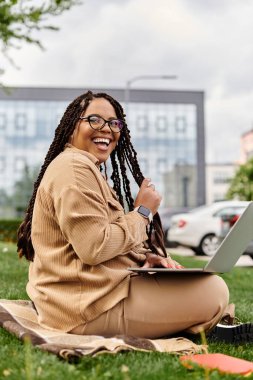 Mutlu bir üniversite öğretmeni parkta dizüstü bilgisayarının keyfini çıkarıyor, güneşin ve temiz havanın tadını çıkarıyor..