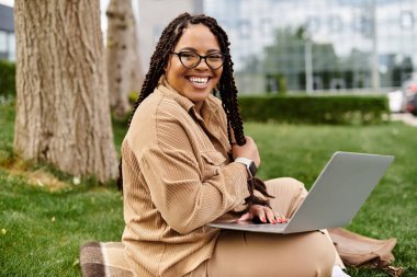 Üniversitede dizüstü bilgisayarı üzerinde çalışırken gülümseyen bir kadın..