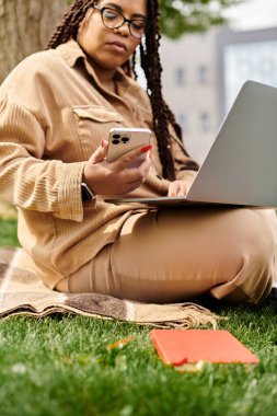 Üniversite öğretmeni doğaya dalmış bir dizüstü bilgisayar ve telefonda çalışıyor..