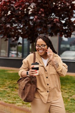 Kendini adamış bir üniversite öğretmeni telefonda kahvenin tadını çıkarırken gülümsüyor ve sohbet ediyor..