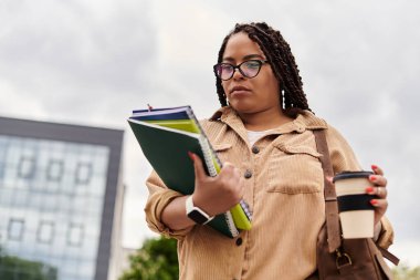 Üniversite öğretmeni elinde defterlerle elinde fincanla dışarı çıktı. Bir sonraki dersini düşündü..