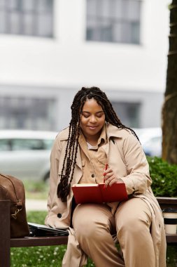 Bir kadın bahçede rahat bir şekilde oturur, doğanın tadını çıkarırken defterine notlar yazar..