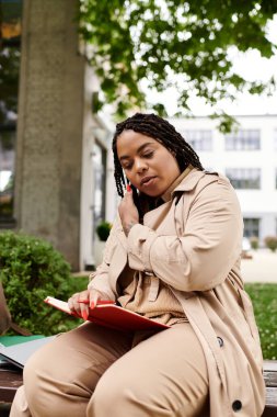 Üniversite eğitimcisi kampüste kitap okurken hevesle fikirleri tartışıyor..
