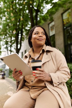 Bir üniversite öğretmeni şehir dışında dinlenir, kahvesini yudumlar ve tablet kullanır..