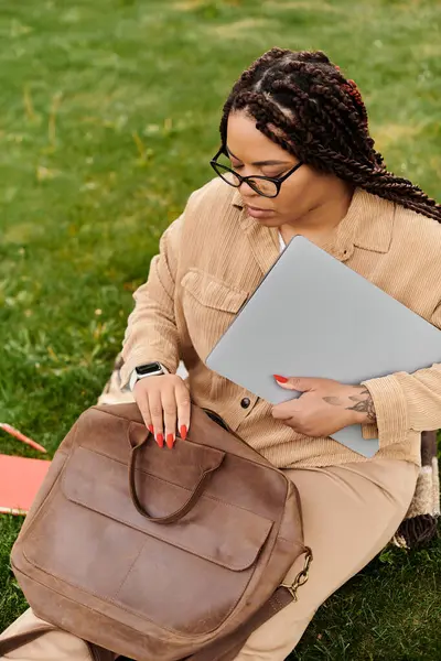 Üniversite öğretmeni notlarını ve bilgisayarını çimlerin üzerinde düzenler ve dışarıda eğlenir..