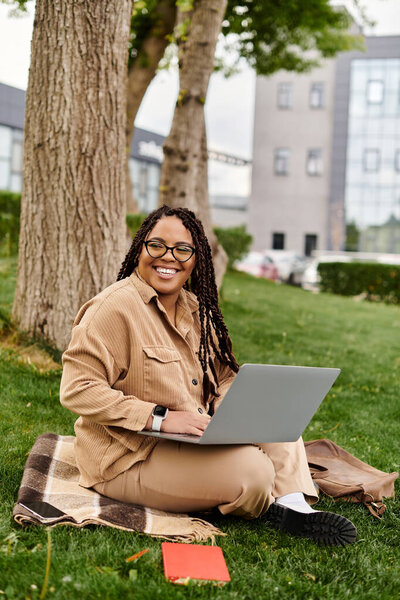 A university teacher enjoys a productive day outdoors, utilizing her laptop under a tree.