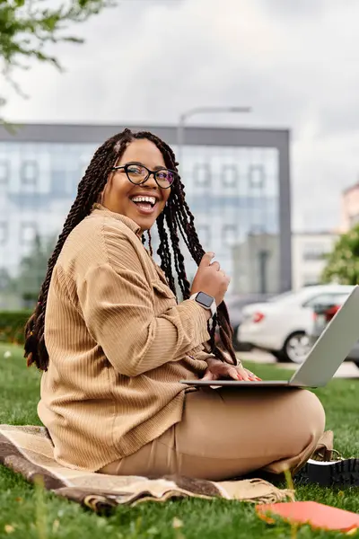 Mutlu bir üniversite öğretmeni parkta dizüstü bilgisayarının keyfini çıkarıyor, güneşin ve temiz havanın tadını çıkarıyor..