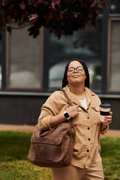 A university teacher strolls across the campus, sipping coffee and carrying a bag, smiling warmly.