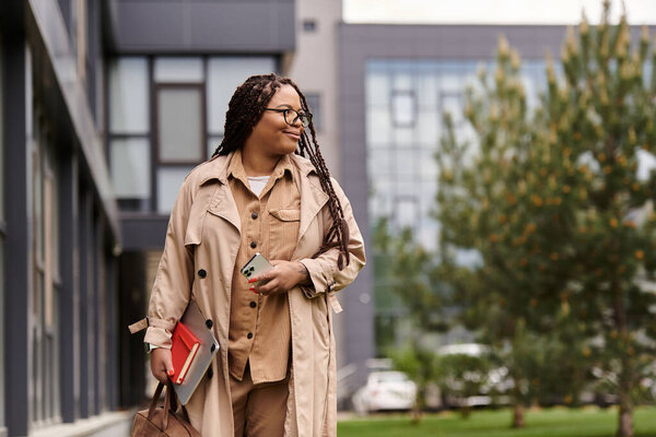 A university teacher strolls through a campus, blending style with intellect while carrying books.