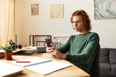 Genç bir adam evinde sakin bir ifadeyle akıllı telefonuna odaklanıyor..
