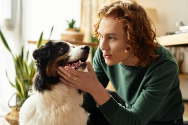 Genç bir adam, sıcak ve davetkar bir yaşam alanında köpeğiyle hassas bir anın tadını çıkarır..