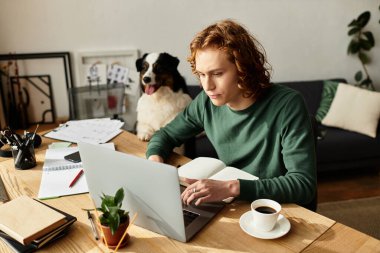 Genç adam sıcak bir fincan kahve ve samimi bir arkadaşlığın tadını çıkarırken evde dizüstü bilgisayarına odaklanıyor..