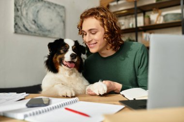 Genç bir adam evde çalışırken neşeli köpeğiyle samimi anlar paylaşır..