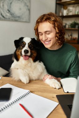 Neşeli bir genç adam işine odaklanırken evdeki köpeğiyle sıcak bir anı paylaşıyor..